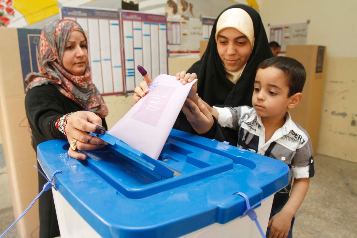An Iraqi woman casts her vote with the help of her son at a polling station on Saturday.
