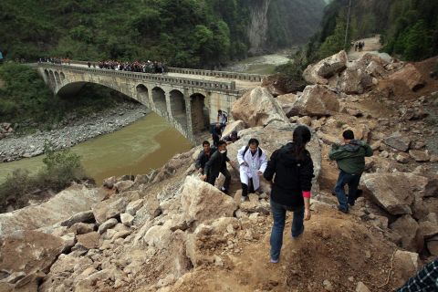 Survivors and rescuers make their way along a damaged area in Lushan on Sunday.