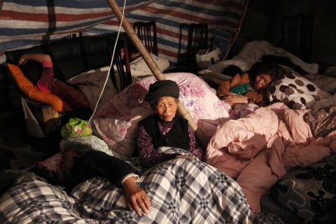 A family rests in a makeshift shelter in Lushan on Sunday.