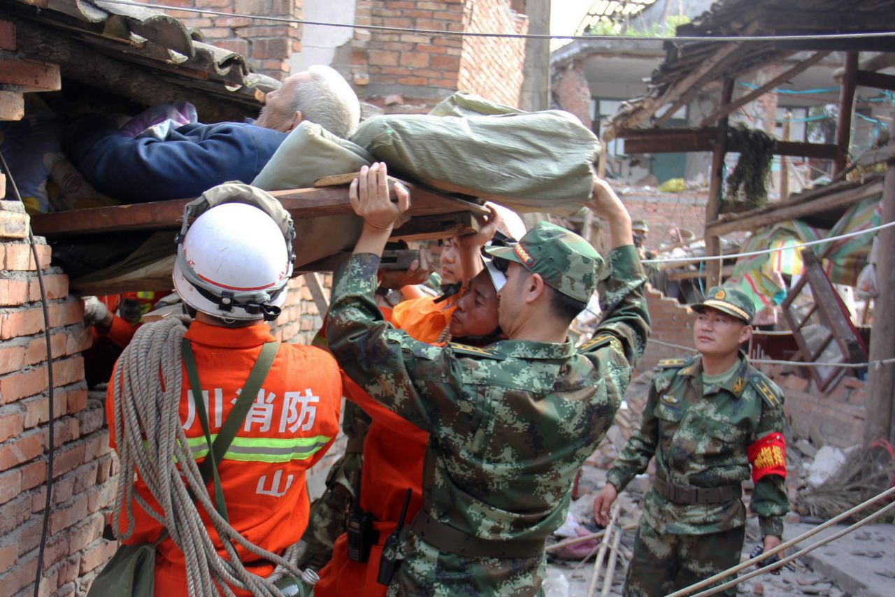 Rescuers carry a paralyzed patient from a collapsed house on Sunday in Qingren township.