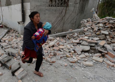 A woman carries her baby through rubble in Lushan County in Sichuan, China, on Sunday, April 21.  