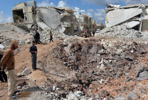 People walk past destroyed houses in the northern Syrian town of Azaz on Sunday, April 21. 