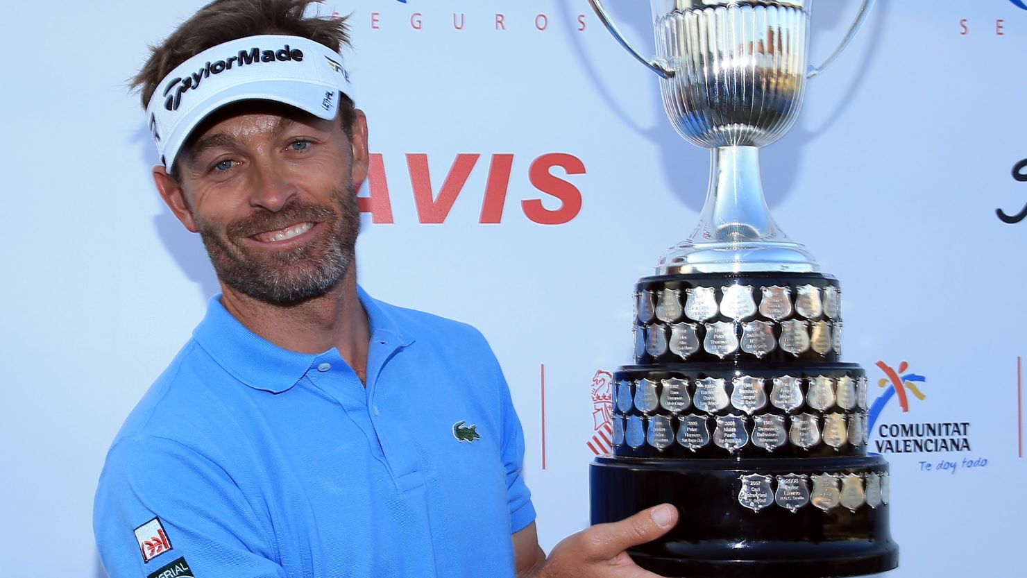 French golfer Raphael Jacquelin poses with the winner's trophy after a marathon playoff at the Open de Espana.