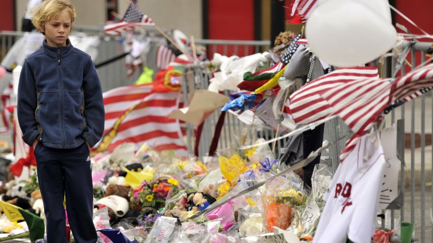 A boy visits a make-shift memorial on Boylston Street on April 20, 2013, near the scene of Boston Marathon explosions as people get back to the normal life the morning after after the capture of the second of two suspects wanted in the Boston Marathon bombings. Thousands of heavily armed police staged an intense manhunt Friday for a Chechen teenager suspected in the Boston marathon bombings with his brother, who was killed in a shootout. Dzhokhar Tsarnaev, 19, defied the massive force after his 26-year-old brother Tamerlan was shot and suffered critical injuries from explosives believed to have been strapped to his body.