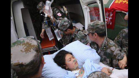 Military medical officers carry a patient to an ambulance at the hospital in Ya'an, China, on Monday.