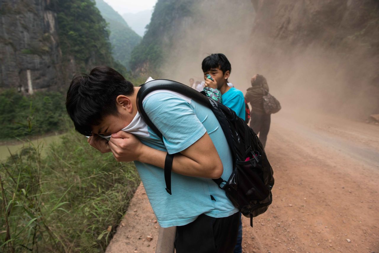 People cover their faces as rocks fall from mountains on their way home to Ya'an on Sunday.