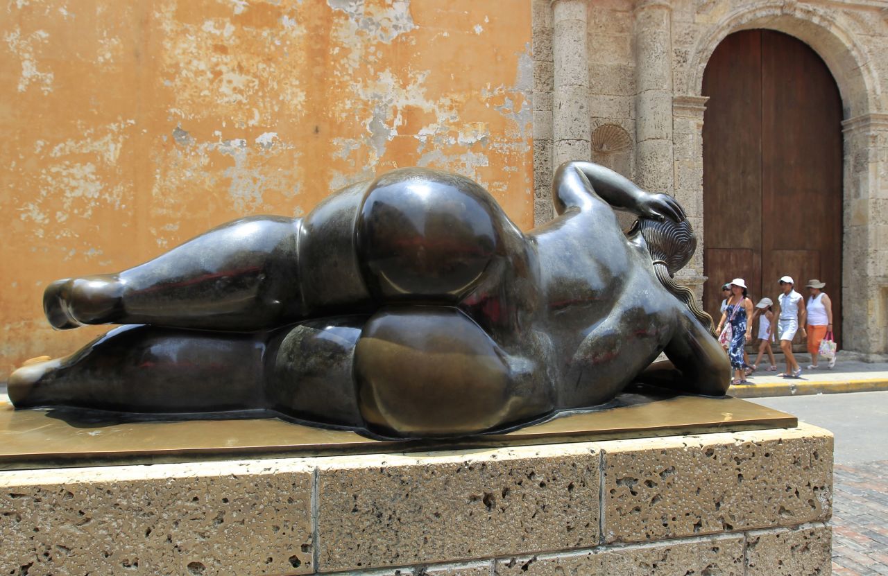 Tourists walk past a sculpture by Fernando Botero in Cartagena's old city in April 2012.