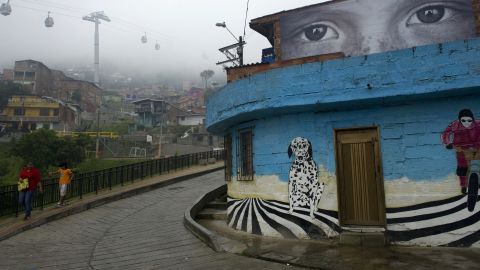 People walk past a giant photograph pasted on a facade at the Commune 1, a shantytown with one of the highest rates of urban violence in Medellin, Antioquia department, Colombia, on January 30, 2012. The municipality of Medellin presented an artistic project called (R)Heroes Without Borders(R), an exhibition of 23 photographs placed in different facades and roofs, to prevent the recruitment of children by illegal groups. AFP PHOTO/Raul ARBOLEDA (Photo credit should read RAUL ARBOLEDA/AFP/Getty Images)