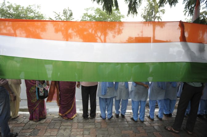 Indian youths stand in front of a banner with the colors of their national flag in a silent demonstration in Hyderabad on April 23.