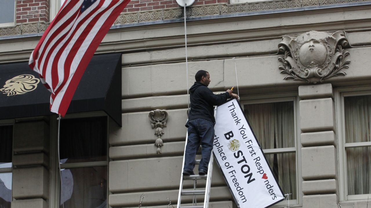 A man removes a sign hanging from the Lennox Hotel along Boylston Street after the street reopened to the public for the first time since the Boston Marathon bombings in Boston on Wednesday, April 24. The city is trying to return to normal less than a week after two bombs exploded near the finish line of the Boston Marathon, shocking the nation and leaving the city on edge. <a href="http://www.cnn.com/SPECIALS/us/boston-bombings-galleries/index.html">See all photography relating to the Boston bombings.</a>