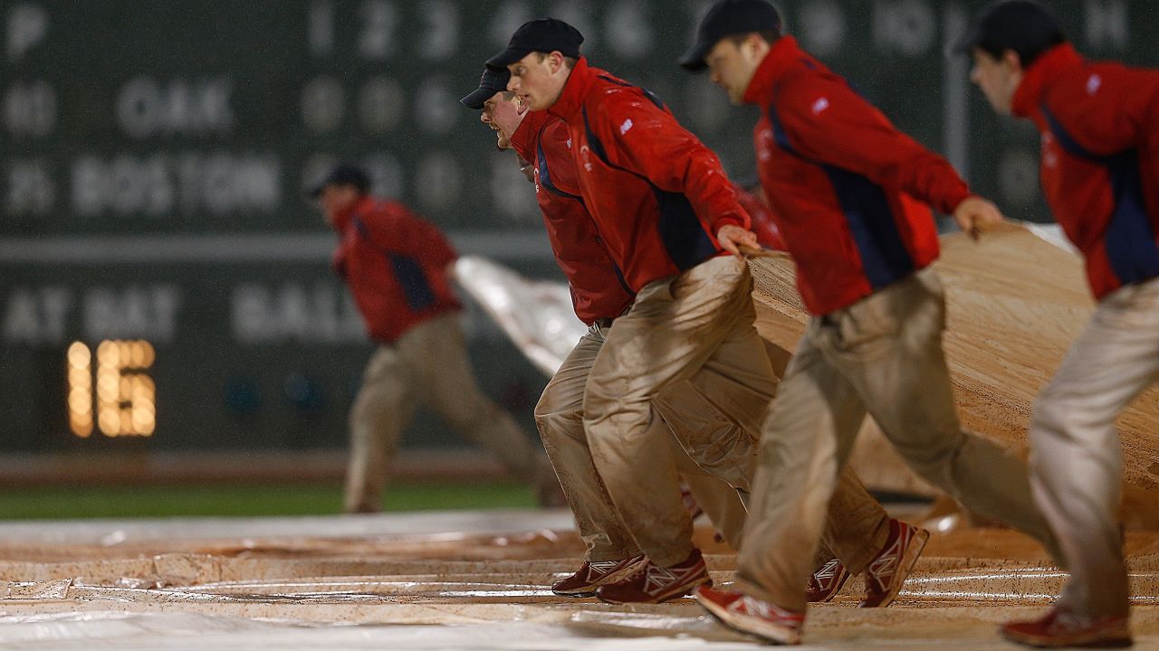 The grounds crew covers the field at Fenway Park in the eighth inning because of rain during a game between the Oakland Athletics and the Boston Red Sox on Tuesday, April 23, in Boston.
