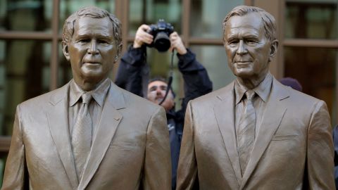 A photographer makes a photo of the two bronze statues of former Presidents George W. Bush and his father, George H.W. Bush, in a courtyard at the Center.