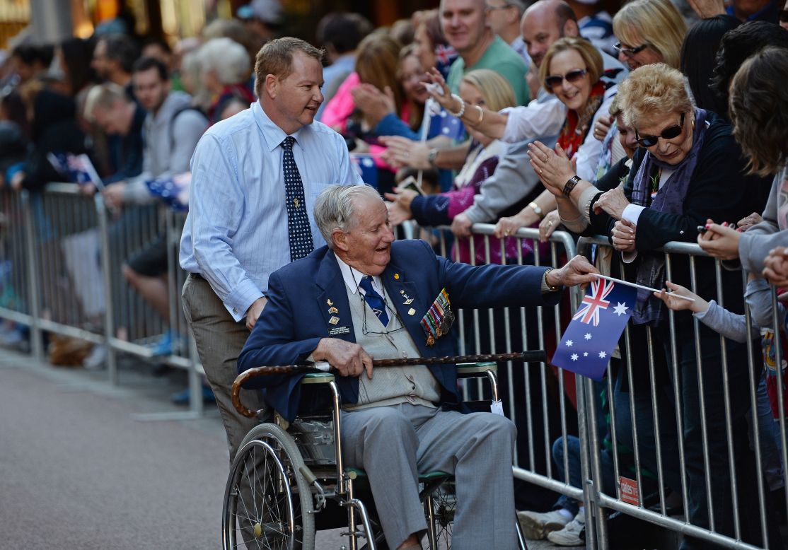 A veteran gives his Australian flag to a spectator during the ANZAC Day parade through Sydney on Thursday. 