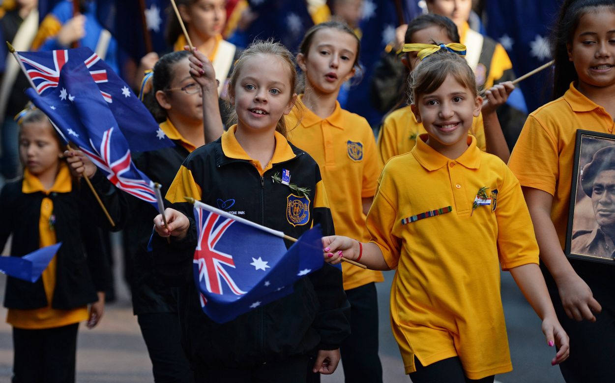 Young children wave flags as they participate in the ANZAC Day march in Sydney on Thursday.