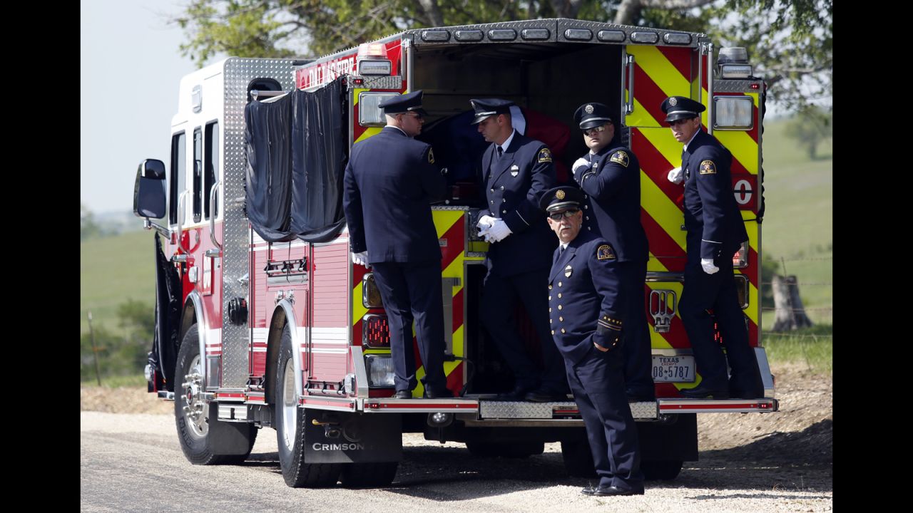 Firefighters stand on the back of a firetruck that transported Harris' body to the Bold Springs Cemetery in West on April 24.