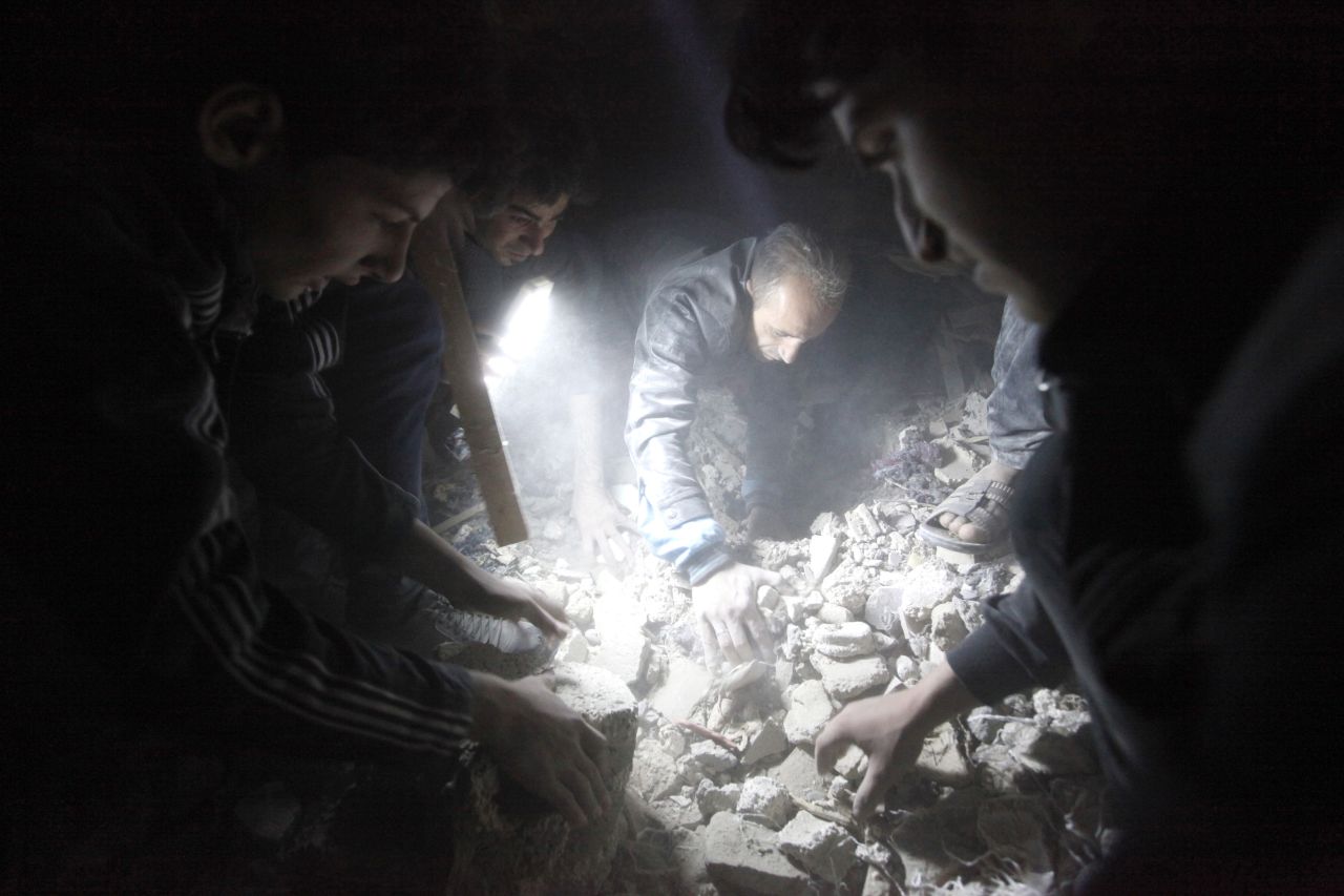 Searchers use a flashlight as they look for  survivors among the rubble created by what activists say was a missile attack from the Syrian regime, in Raqqa province, Syria, on April 25. 