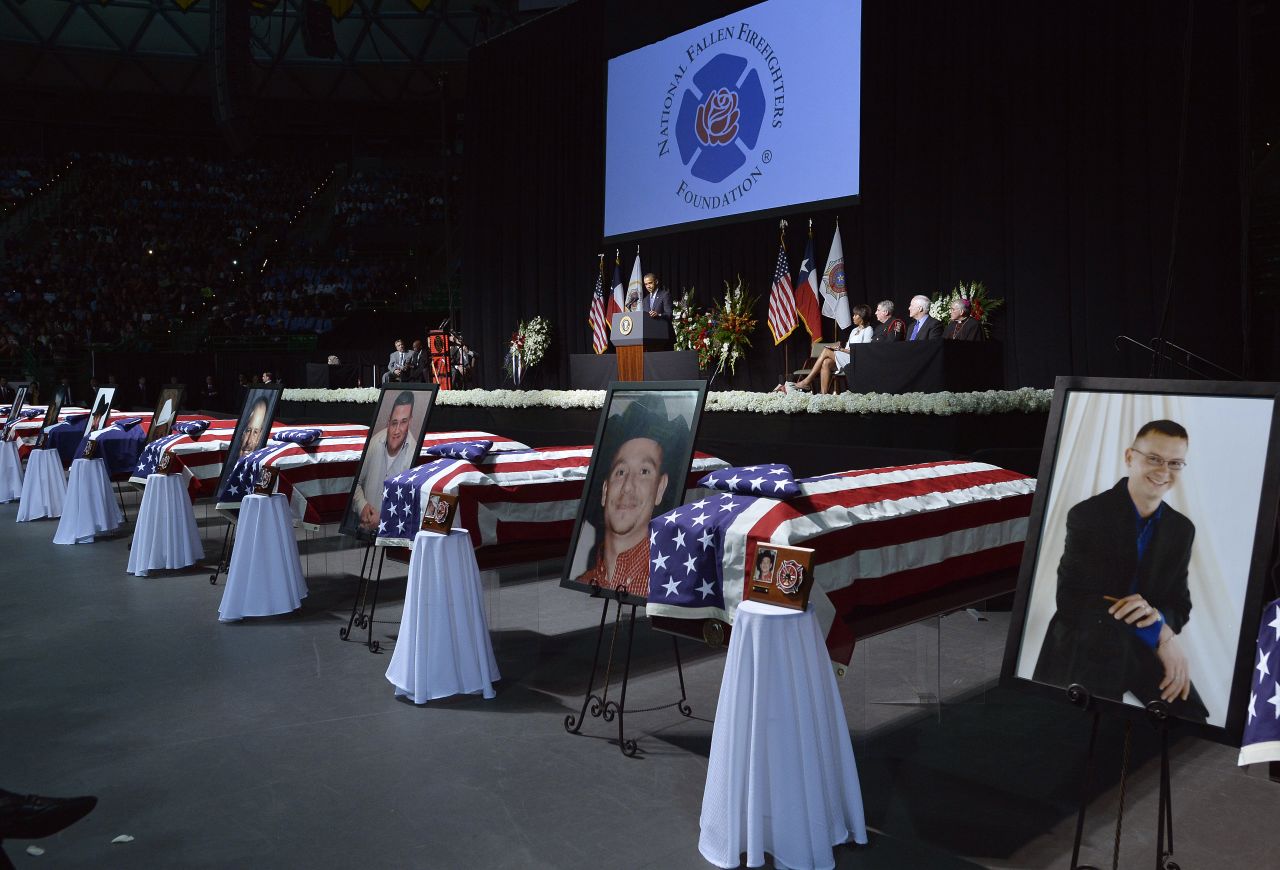 Photos of the fallen firefighters stand next to their coffins at the memorial on April 25.