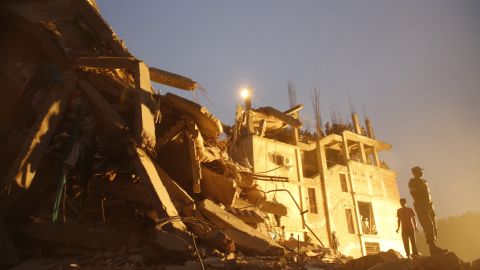 Rescue workers stand on the rubble of the collapsed building on April 26.