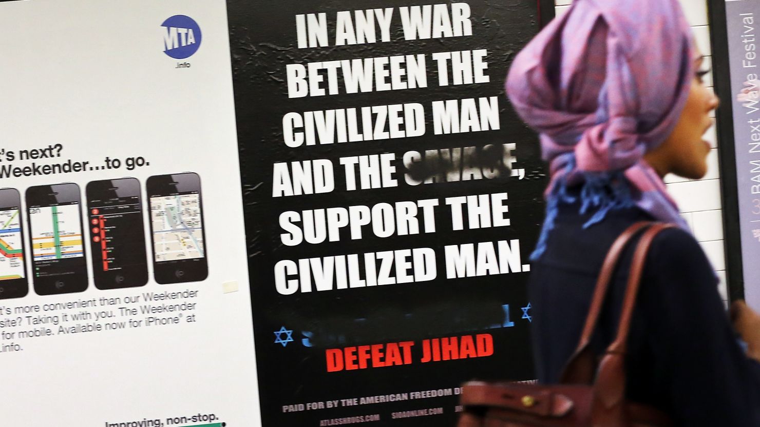 A woman walks by a controversial ad in a New York subway station last fall. The word "savage" had been defaced.