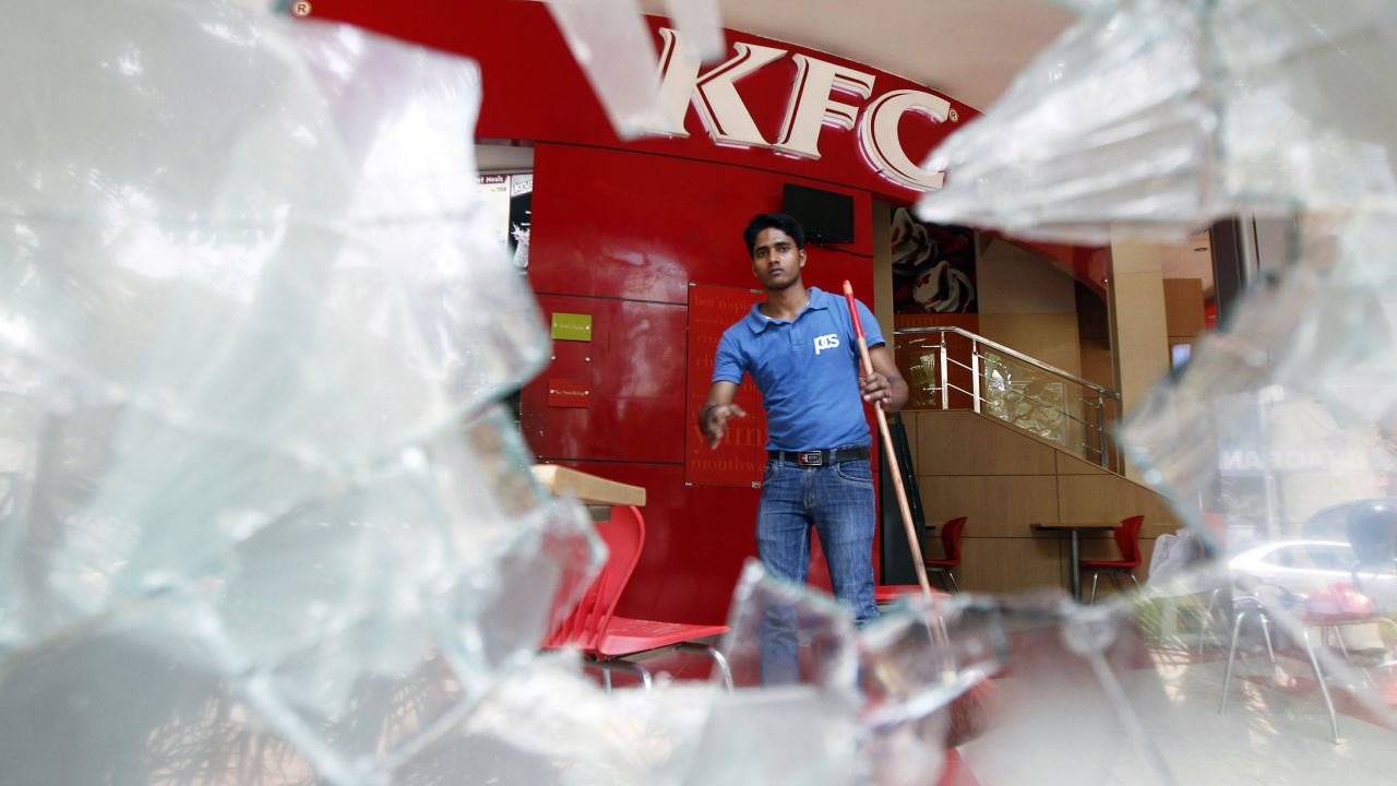 A man cleans up a restaurant after protesters broke its windows.