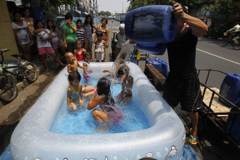 A man pours water over children swimming in an inflatable swimming pool to beat the heat in Manila, Philippines, on Friday, April 26.