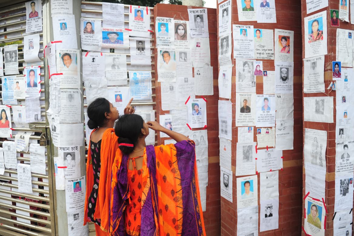 Two Bangladeshi women look at a board with notices posted of missing and dead workers on April 27.