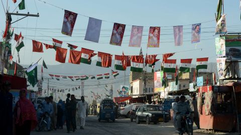 Commuters pass under the flags and posters of political parties in Quetta, Pakistan, on Sunday.