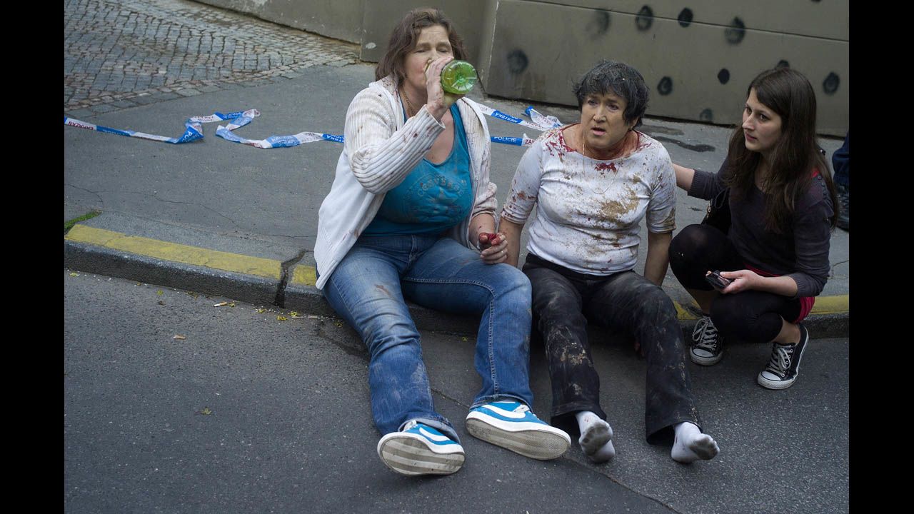 Two women injured in the explosion sit on the sidewalk.
