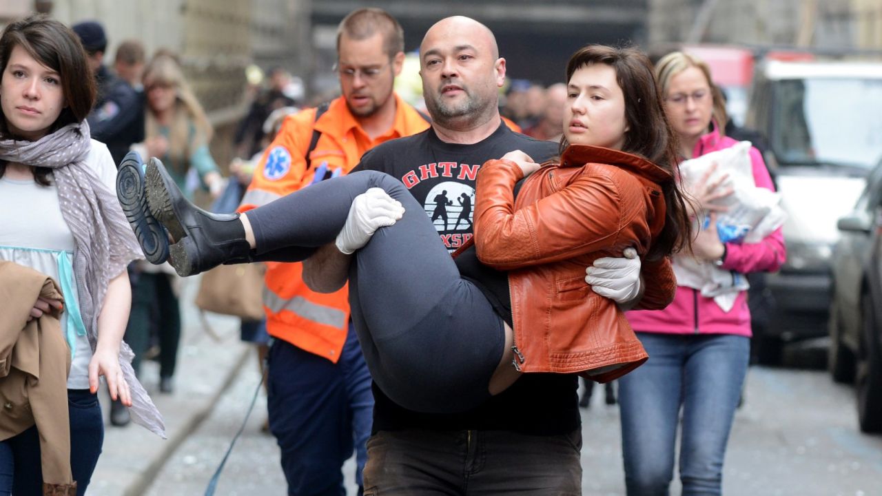 A man carries a young woman injured by a powerful gas blast in Prague's historic center on April 29, 2013.
