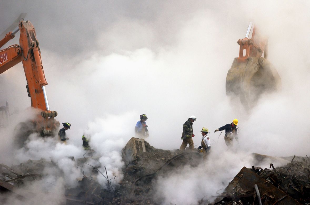 Firefighters make their way over the ruins through clouds of smoke at ground zero on October 11, 2001.