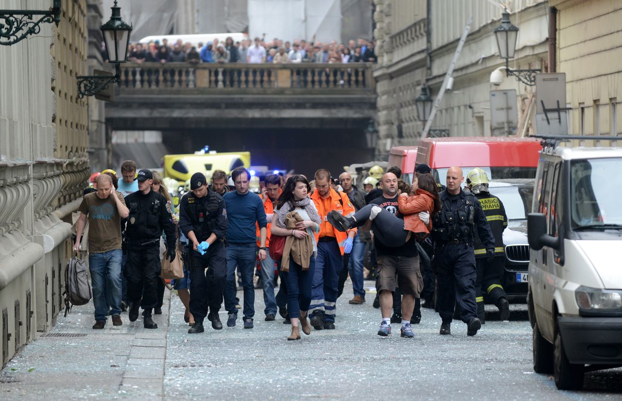 Police officers, paramedics and firefighters lead injured people away from the scene of a powerful gas explosion at a building in the historic center of Prague, Czech Republic, on Monday, April 29. The blast injured at least 35 people.
