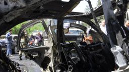 Caption:  A Syrian officer is seen through the wreckage of a vehicle following an explosion in the Mazzeh district of the Syrian capital Damascus on April 29, 2013, which is believed to have targeted the prime minister's convoy. Syrian Prime Minister Wael al-Halqi escaped an assassination bid, surviving a blast that targeted his convoy in Damascus, Syrian state television reported. AFP PHOTO/ LOUAI BESHARA (Photo credit should read LOUAI BESHARA/AFP/Getty Images)  