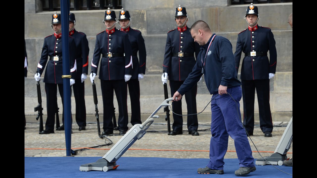 A cleaner vacuums the carpet outside the Royal Palace during Queen Beatrix's abdication ceremony.