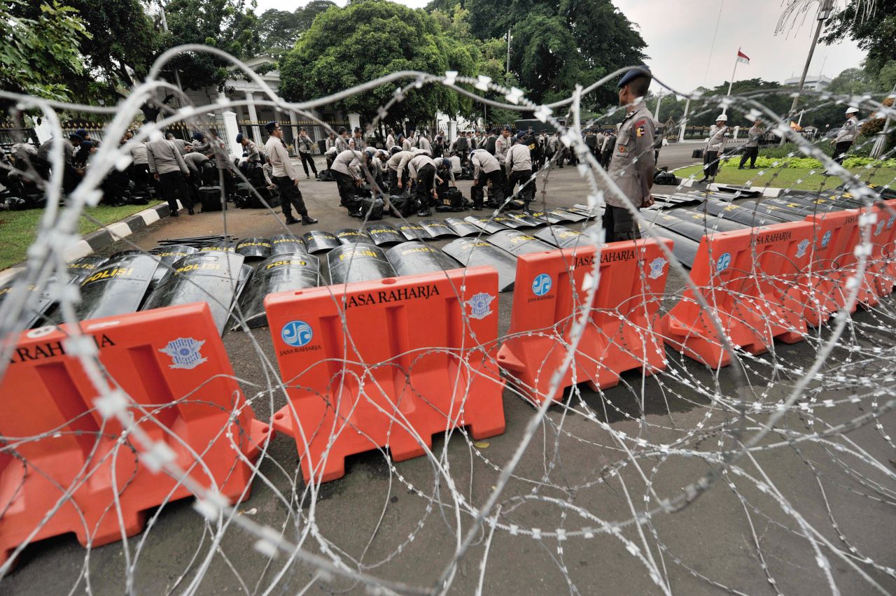 Police prepare behind a line of barbed wire before thousands of Indonesian workers arrive outside the presidential palace in Jakarta.