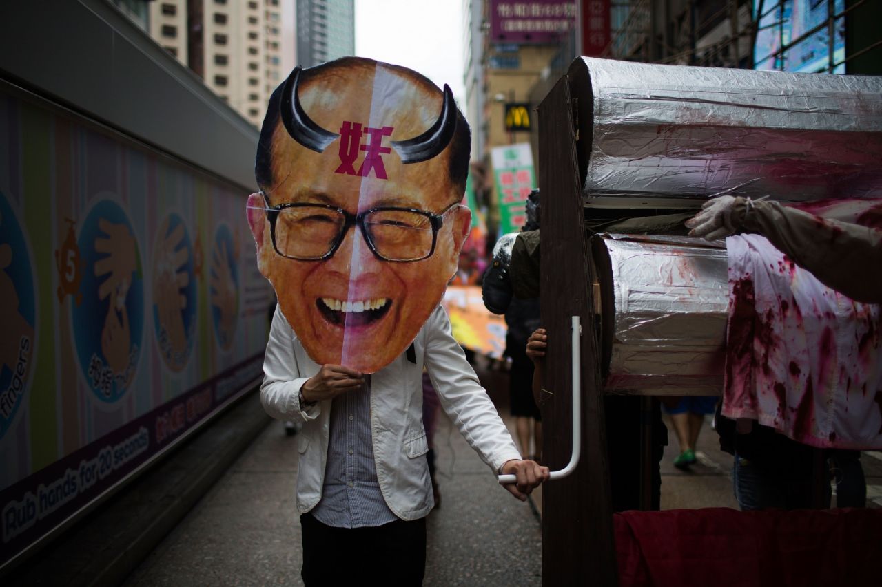 A protestor holds an oversized mask of billionaire tycoon Li Ka-shing, the chairman of Hutchison Whampoa, as hundreds of dock workers protest pay and working conditions in Hong Kong.
