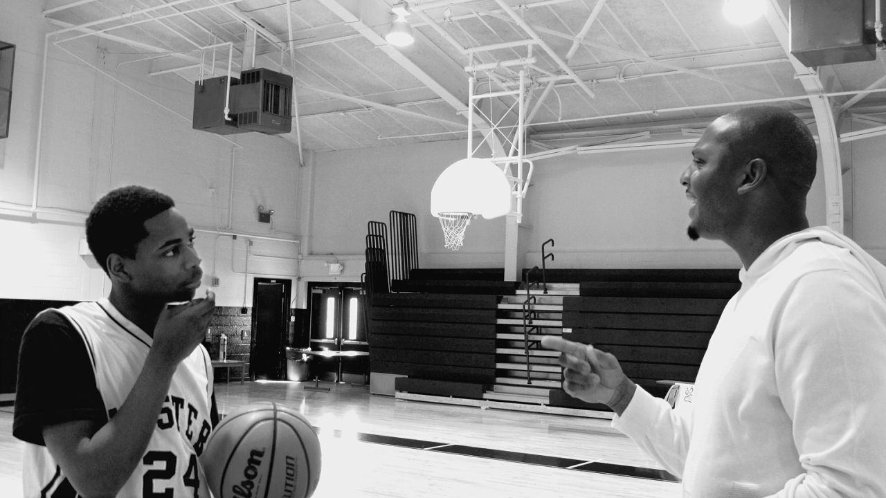 Coach Penny provides tips to Reggie Green. Under Penny's leadership, Reggie's game improved along with his grades.