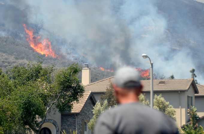 A resident watches as a wildfire approaches homes in Newbury Park.
