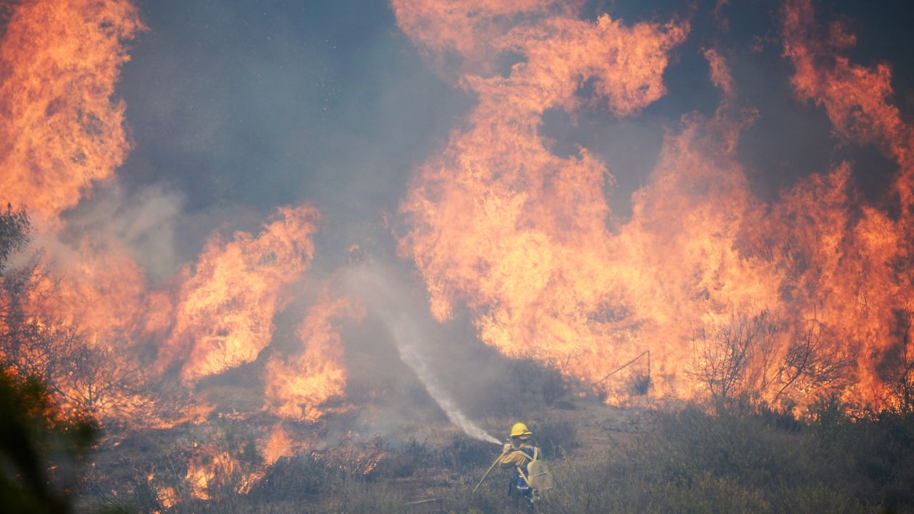 A firefighter works against a wall of flames from an out-of-control wildfire on Thursday, May 2, in Camarillo, California.