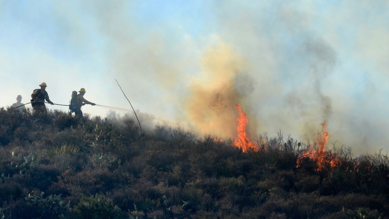 Firefighters put out hot spots on a hillside behind homes in Newbury Park on May 2.