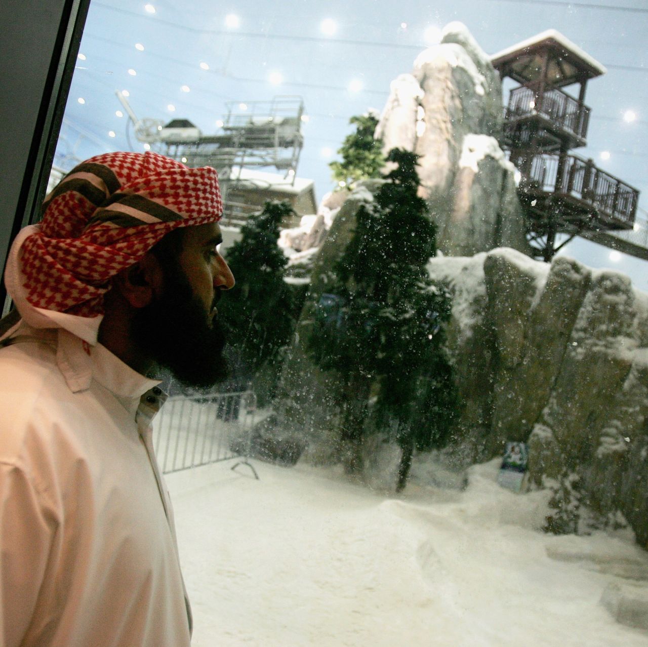 A gentleman wearing a traditional Emiratian dishdasha looks through a glass window at the Ski Dubai snowdome at Mall of the Emirates. The snowdome is billed as the world's largest. 