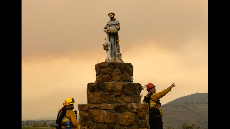 San Bernardino County firefighters observe the wildfire next to a statue of St. Francis of Assisi on May 3 in Hidden Hills, California. Thousands of homes are threatened by the growing wildfire northwest of Los Angeles that has forced the closure of the scenic coastal highway.