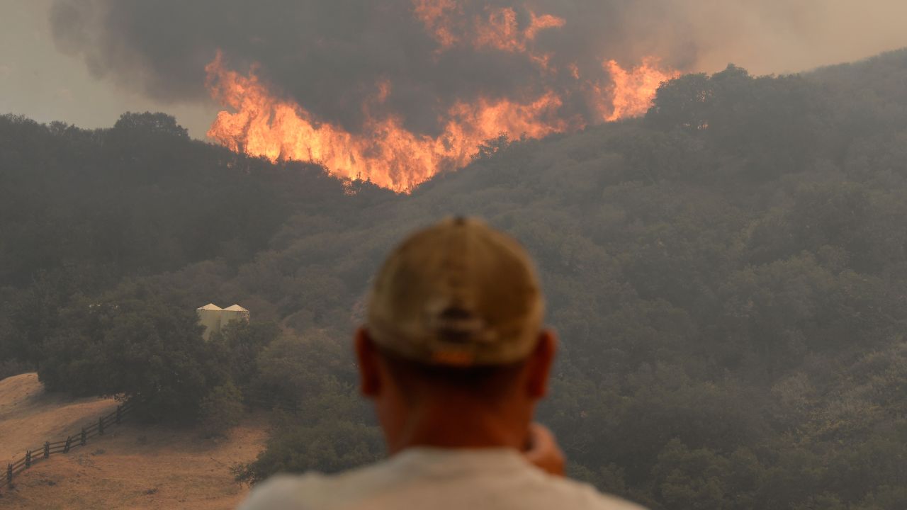 A man takes a photo of the wall of flames on May 3 in Hidden Hills.