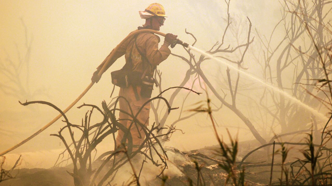 A firefighter sprays water on a flareup along the Pacific Coast Highway in Point Mugu, California, on May 3.