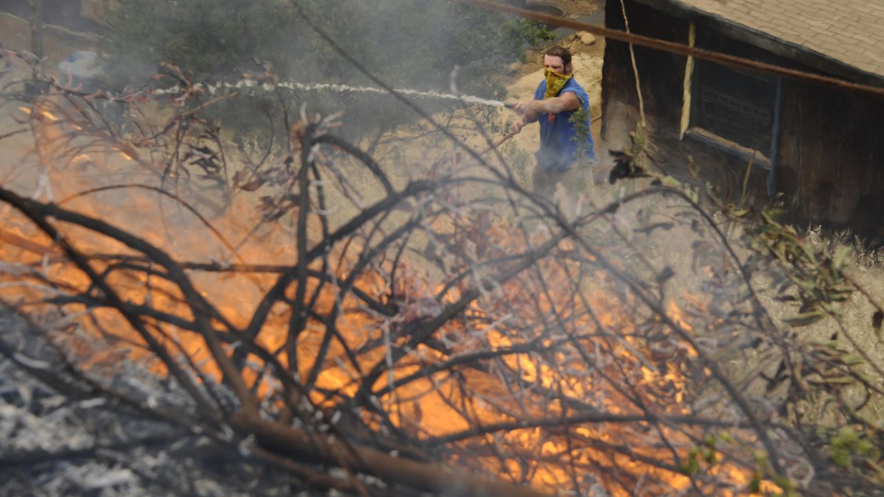 Homeowner Brian Bonsant uses a hose as flames get close to his barn during the second day of the Springs Fire in the mountain areas of Ventura County, California, on May 3. Hundreds of firefighters continue to battle wind and dry conditions as the fires continue to burn.