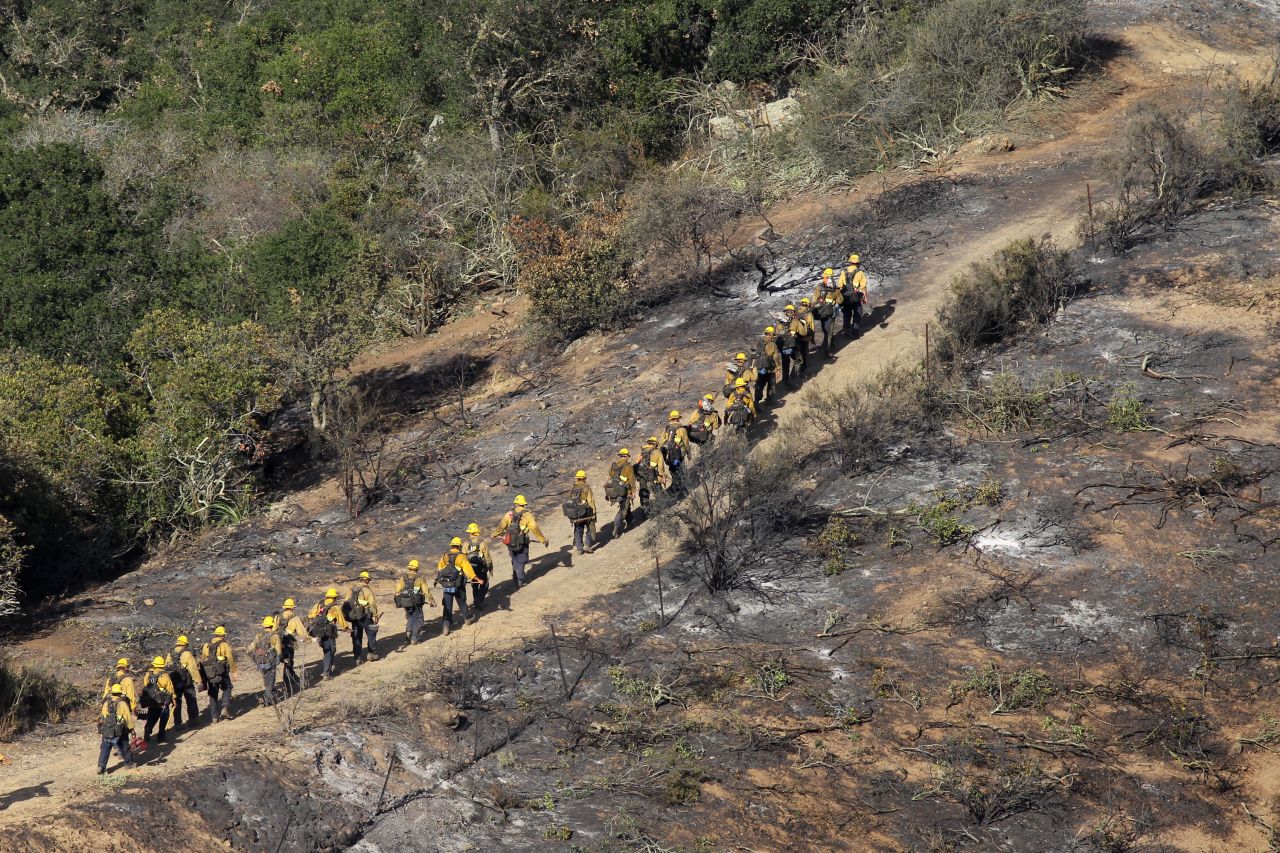 U.S. Forest Service Hotshot firefighters walk along the edge of the fire near Hidden Valley on May 4.