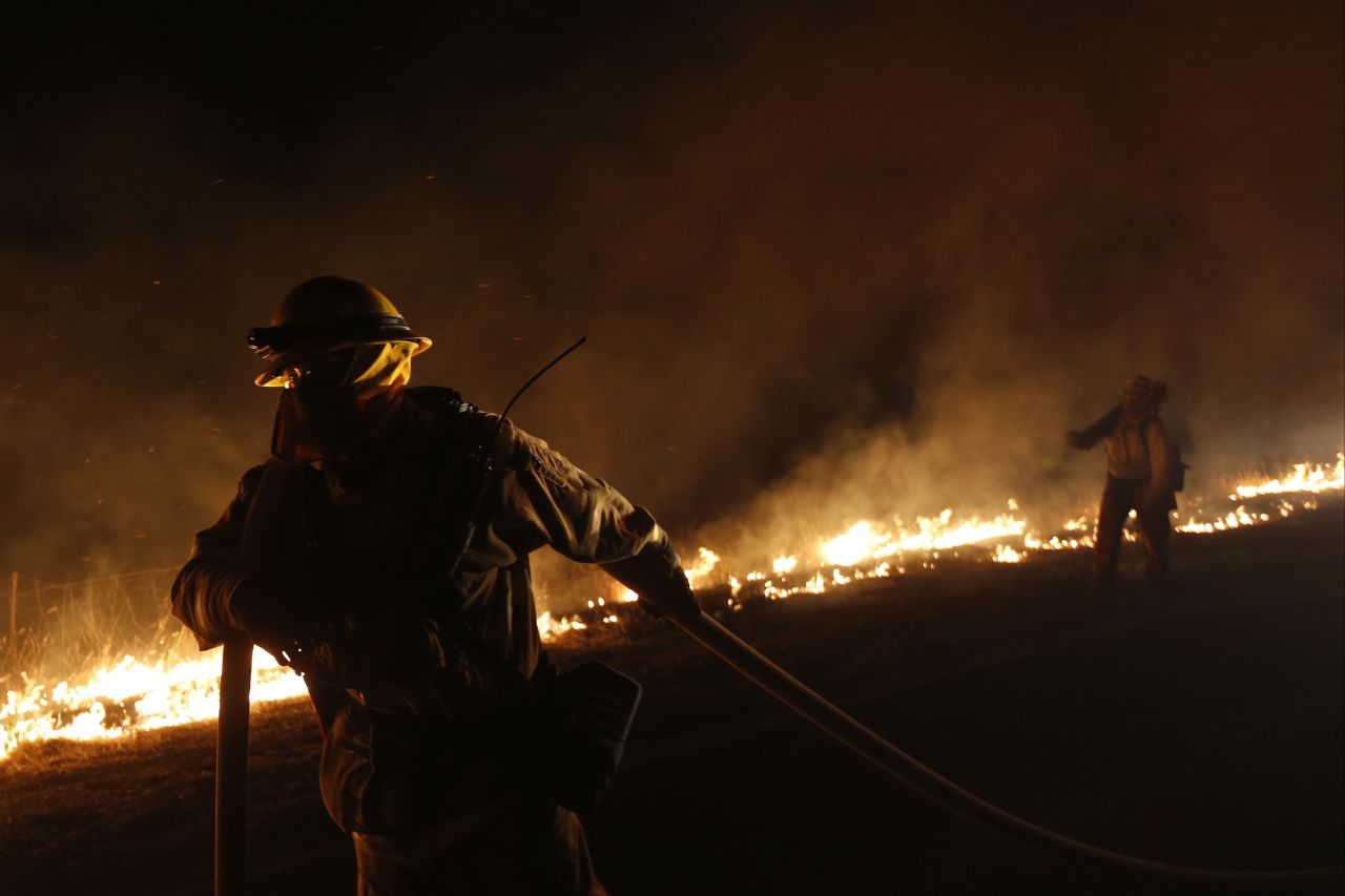 A firefighter pulls a hose line near a backfire while fighting the Springs Fire on May 4.