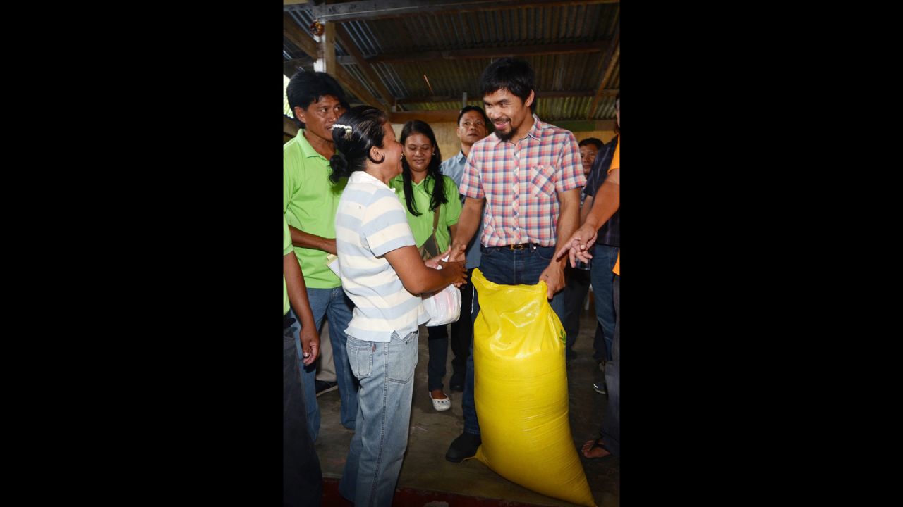 Pacquiao gives a sack of rice and relief goods to a woman after floods struck in Glan, Sarangani province, southern Philippines, June 17, 2012. 