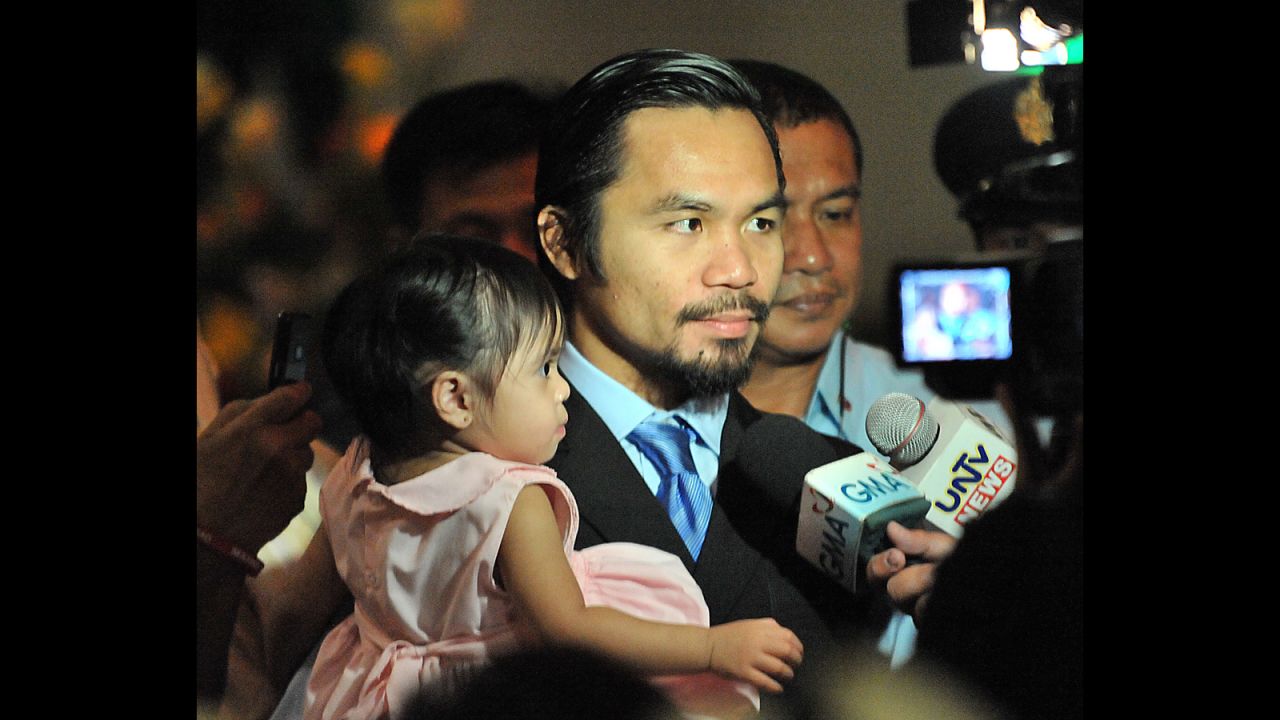 Pacquiao holds his daughter Queen Elizabeth as he talks to members of the media during his victory party for winning a seat in parliament -- held jointly with her birthday celebration -- at a convention center on the southern island of Mindanao on May 15, 2010. 