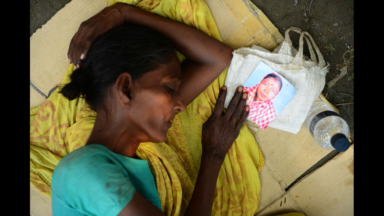 A woman holds a portrait of her missing relative as she sleeps on Saturday, May 4.