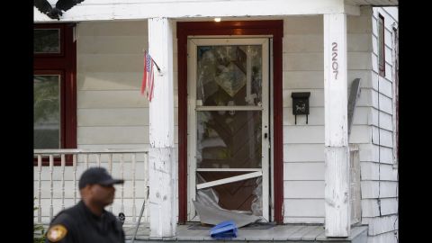A police officer stands in front of the broken front door of the house on May 7, 2013, where the kidnapped women escaped.